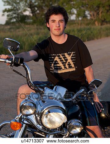 Stock Photo - Young man on a motorcycle at Lake of the Woods, Ontario. Fotosearch