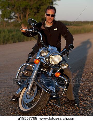 Stock Photo - Young man on a motorcycle at Lake of the Woods, Ontario. Fotosearch