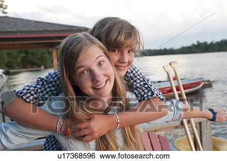 Younger girl embracing her older sister at Lake of the Woods, Ontario View Large Photo Image Stock Photograph - Younger girl embracing her older sister at Lake of the Woods, Ontario. Fotosearch
