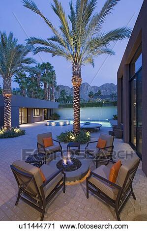 Stock Image - Lit firepit with chairs on terrace of California home. Fotosearch