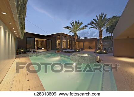 Stock Photo - LIt pool and exterior of Californian home. Fotosearch