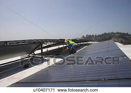 Stock Image - Maintenance worker checks solar array on rooftop in Los Angeles, California. Fotosearch