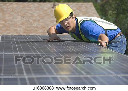 Stock Photo - Maintenance worker measures solar array on rooftop, Los Angeles, California. Fotosearch