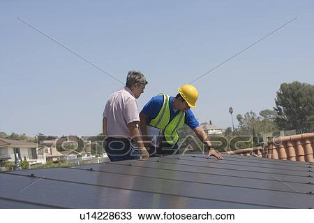 Maintenance workers stand with solar array on rooftop in Los Angeles, California View Large Photo Image Stock Image - Maintenance workers stand with solar array on rooftop in Los Angeles, California. Fotosearch