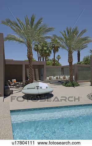 Stock Image - Seating with palm trees on poolside of Californian home. Fotosearch