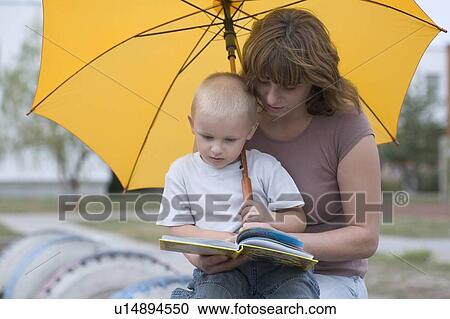Young boy and woman sit under yellow umbrella reading a book View Large Photo Image Stock Image - Young boy and woman sit under yellow umbrella reading a book. Fotosearch