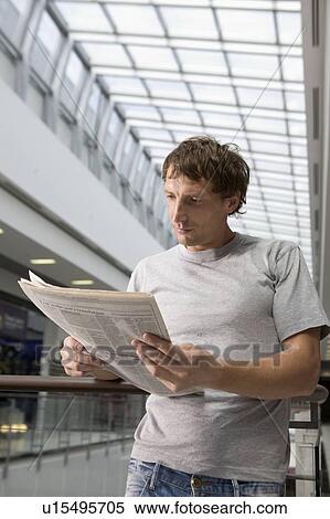 Young man stands reading newspaper in new shopping centre, Voronezh View Large Photo Image Stock Photography - Young man stands reading newspaper in new shopping centre, Voronezh. Fotosearch