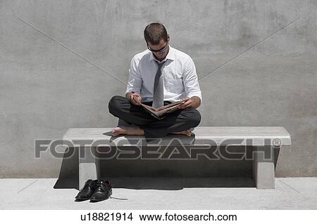 Barefoot businessman sitting on bench reading newspaper View Large Photo Image Picture - Barefoot businessman sitting on bench reading newspaper. Fotosearch