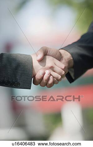Stock Image - Business man and woman shaking hands. Fotosearch