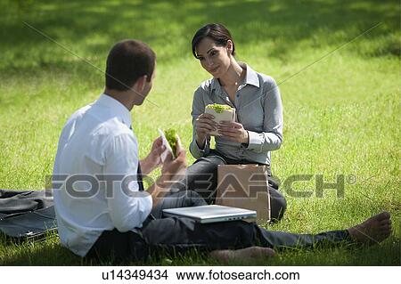 Picture - Business people eating lunch on grass. Fotosearch