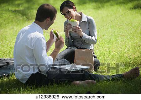 Stock Photograph - Business people eating lunch on grass. Fotosearch
