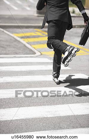 Businessman in suit inline skating across road View Large Photo Image Stock Image - Businessman in suit inline skating across road. Fotosearch