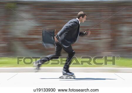 Stock Image - Businessman in suit inline skating. Fotosearch