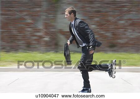 Stock Photo - Businessman in suit inline skating. Fotosearch