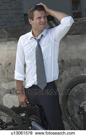 Businessman in suit next to broken bicycle View Large Photo Image Stock Photo - Businessman in suit next to broken bicycle. Fotosearch