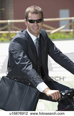 Businessman in suit riding bicycle to work View Large Photo Image Stock Image - Businessman in suit riding bicycle to work. Fotosearch