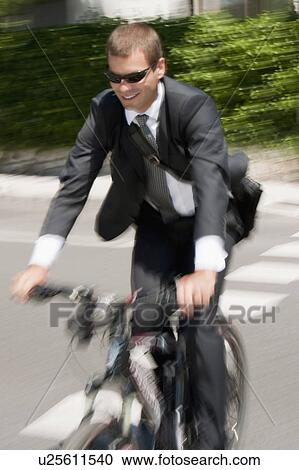 Businessman in suit riding bicycle to work View Large Photo Image Stock Image - Businessman in suit riding bicycle to work. Fotosearch
