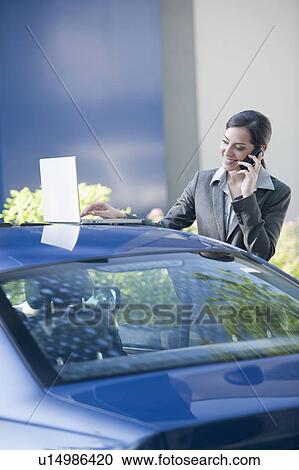 Businesswoman next to car with laptop talking on smartphone View Large Photo Image Stock Image - Businesswoman next to car with laptop talking on smartphone. Fotosearch