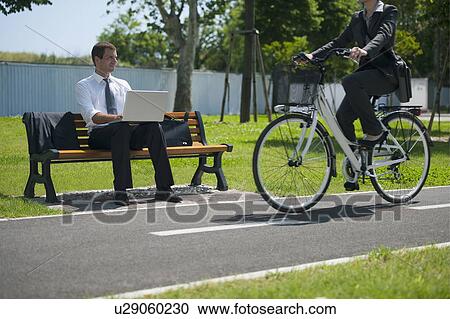 Businesswoman on bike passing a businessman outdoors View Large Photo Image Stock Image - Businesswoman on bike passing a businessman outdoors. Fotosearch