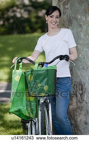 Stock Image - Casual woman with bicycle and reusable shopping bags. Fotosearch