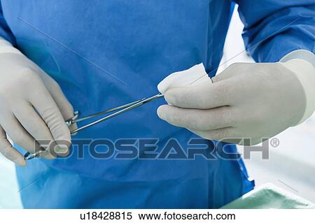 Stock Photography - Close up of surgeon with forceps and gauze in his hands. Fotosearch