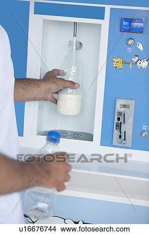 Picture - Closeup of man's hands filling milk bottle at cooler. Fotosearch