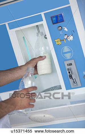 Stock Photography - Closeup of man's hands filling milk bottle at cooler. Fotosearch