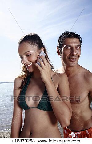 Couple on the beach; female on cell phone View Large Photo Image Stock Photo - Couple on the beach; female on cell phone. Fotosearch