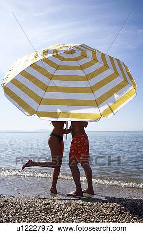 Couple on the beach under umbrella View Large Photo Image Stock Image - Couple on the beach under umbrella. Fotosearch