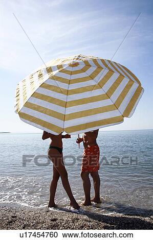 Stock Image - Couple on the beach under umbrella. Fotosearch