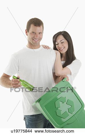 Couple throwing glass bottle in the recycling bin View Large Photo Image Picture - Couple throwing glass bottle in the recycling bin. Fotosearch