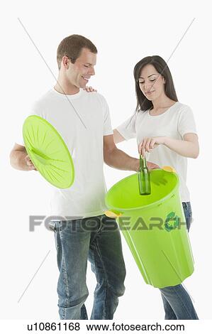 Stock Photo - Couple throwing glass bottle in the recycling bin. Fotosearch