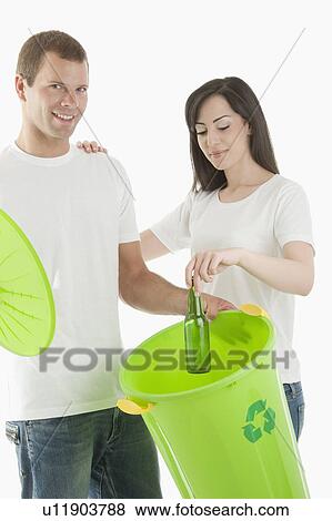 Couple throwing glass bottle in the recycling bin View Large Photo Image Stock Photo - Couple throwing glass bottle in the recycling bin. Fotosearch