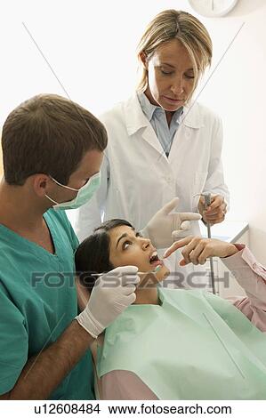 Picture - Dental professionals with patient pointing to mouth. Fotosearch