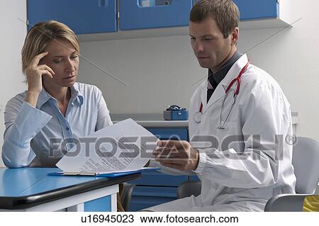 Stock Image - Doctor and patient looking at document. Fotosearch