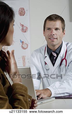 Stock Photography - Doctor at laptop with patient in office. Fotosearch
