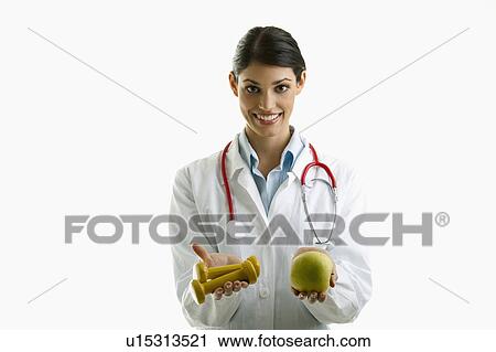Doctor holding apple and hand weights View Large Photo Image Stock Image - Doctor holding apple and hand weights. Fotosearch