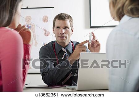 Stock Image - Doctor holding bottle of pills for patients. Fotosearch