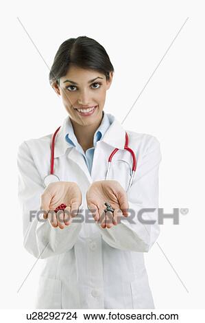 Picture - Doctor holding pills in each hand. Fotosearch