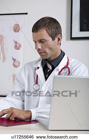 Stock Photograph - Doctor in his office with circulatory system chart and laptop. Fotosearch