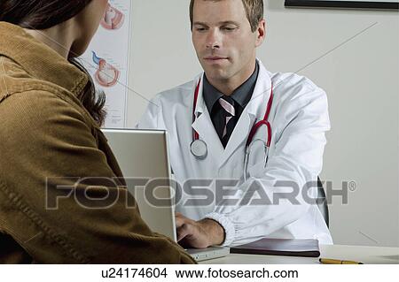 Doctor on laptop with patient in office View Large Photo Image Picture - Doctor on laptop with patient in office. Fotosearch