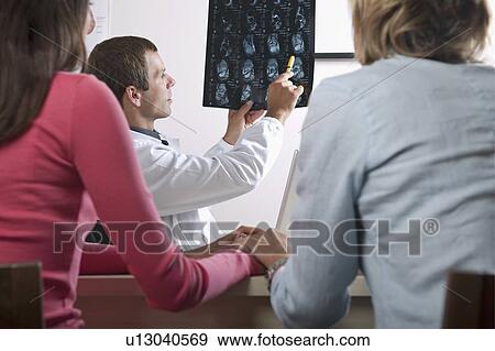 Stock Photo - Doctor showing MRI to patient . Fotosearch