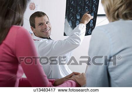 Stock Photo - Doctor showing MRI to patient . Fotosearch