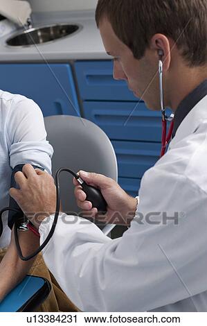 Stock Image - Doctor taking patient's blood pressure. Fotosearch