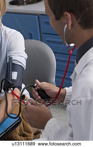 Doctor taking patient's blood pressure View Large Photo Image Stock Photo - Doctor taking patient's blood pressure. Fotosearch