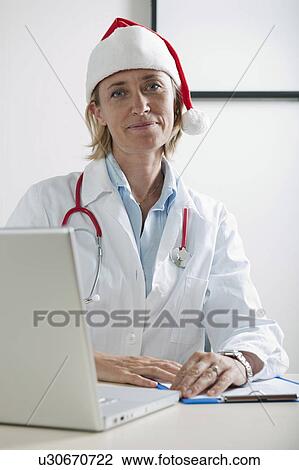 Doctor with laptop and Santa's hat View Large Photo Image Stock Image - Doctor with laptop and Santa's hat. Fotosearch