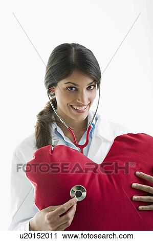 Doctor with stethoscope on heart pillow View Large Photo Image Stock Image - Doctor with stethoscope on heart pillow. Fotosearch