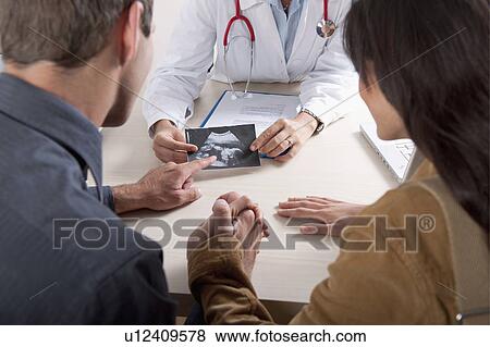 Stock Photo - Doctor with ultrasound and couple. Fotosearch
