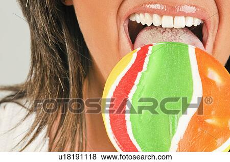 Stock Photo - Female adult closeup eating a lollipop. Fotosearch