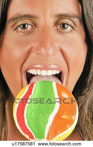 Female adult eating a lollipop View Large Photo Image Stock Image - Female adult eating a lollipop. Fotosearch